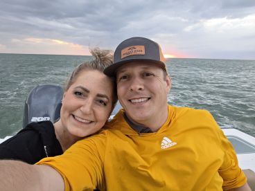 A couple enjoys a sunset selfie on a boat, capturing a memorable moment on the water — perfect for romantic outings or adventures.