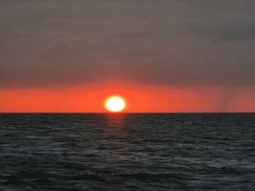 A breathtaking sunset over the ocean, showcasing vibrant hues of orange and red — a perfect backdrop for evening boat cruises.