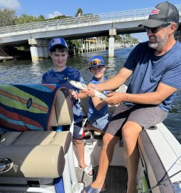 A joyful moment as two children proudly display their catch while fishing on a boat, creating lasting family memories on the water.