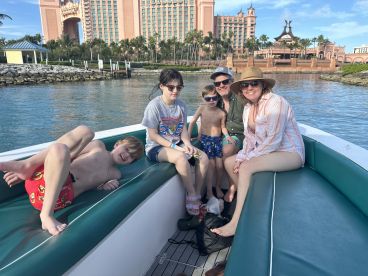 A joyful family enjoys a day on the water, capturing fun moments aboard a boat with a stunning backdrop of tropical scenery.