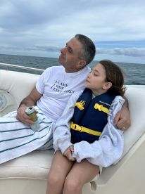A father and daughter enjoy a peaceful moment together on a boat, surrounded by the ocean — a perfect snapshot of family bonding on the water.