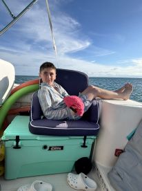A young boy relaxes in a comfortable seat aboard a boat, showcasing the cozy interior space perfect for lounging during a day on the water.