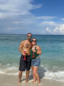A couple enjoys cocktails on the beach, capturing a joyful moment against the backdrop of turquoise waters — perfect for romantic getaways or beach celebrations.