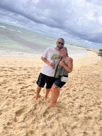 A happy couple poses together on the beach, enjoying a moment of celebration by the water — perfect for romantic getaways or beach vacations.