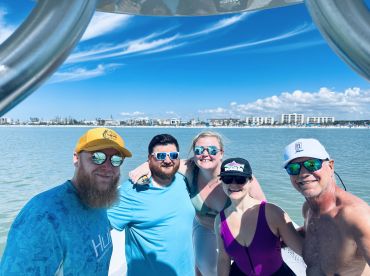 A cheerful group of friends poses for a photo on a boat, enjoying a sunny day on the water — perfect for memorable outings and celebrations.