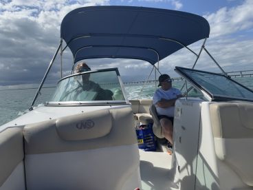Two individuals enjoy a day on the water from the helm of a boat, showcasing the comfortable seating and steering area, perfect for navigating scenic waterways.