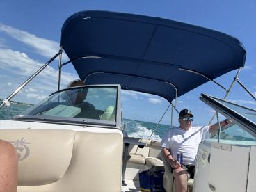 Two individuals enjoy a day on the water aboard a boat, showcasing a relaxed atmosphere and the beauty of the open sea.