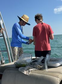 Two individuals engage in fishing activities aboard a boat, showcasing a fun and interactive experience on the water.