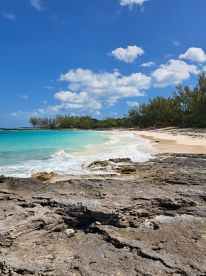 A stunning view of a secluded beach with turquoise waters and rocky shoreline, perfect for a relaxing getaway or exploration in the Bahamas.