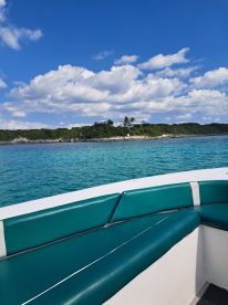 A view of the comfortable seating area inside a boat, showcasing the turquoise upholstery against a backdrop of clear blue waters and a scenic island in the distance.