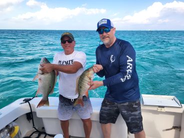Two anglers proudly display their catch while fishing in the beautiful ocean waters, showcasing the thrill of a successful day on the water.