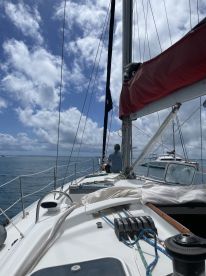 A serene moment aboard a sailboat, with a guest enjoying the view of the ocean and clouds — perfect for sailing enthusiasts and adventure seekers.