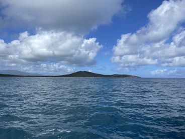 A stunning view of a distant island under a dramatic sky, showcasing the beauty of the coastline and inviting waters — perfect for island hopping adventures.