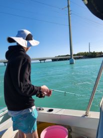 A young boy enjoys fishing from a boat in clear turquoise waters, showcasing the excitement of a day on the water.