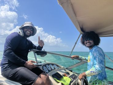 Two crew members smile and pose aboard a boat, showcasing a fun and friendly atmosphere on the water.