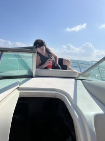 A woman relaxes on the deck of a boat, enjoying a drink under the sunny sky — a perfect moment for leisure on the water.