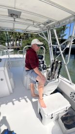 A man sits at the helm of a boat, showcasing the interior design and seating arrangement, ideal for navigating the waters.