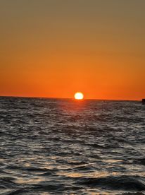 A breathtaking sunset over the ocean, casting vibrant hues across the water — a perfect moment for relaxation and reflection on a boating adventure.