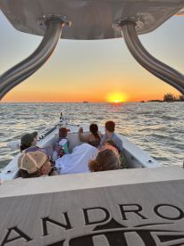 A group of family and friends enjoy a stunning sunset from their boat, creating a perfect backdrop for memorable moments on the water.