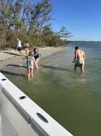 A joyful group of friends and family enjoys a fun day at the beach, splashing in the water and making memories under the sun.