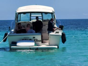 A group enjoys a day on the water aboard a boat, with one person cooking while others relax — perfect for family outings and fun on the sea.