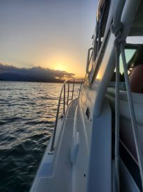 A stunning sunset view from the side of a boat, capturing the serene waters and the silhouette of the vessel — perfect for evening cruises.