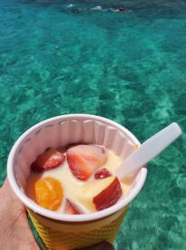 A refreshing cup of fruit salad enjoyed by the water, perfect for a sunny day on a boat trip. Ideal for keeping cool and energized during aquatic adventures.