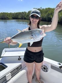 A woman proudly displays her catch while fishing from a boat, showcasing the thrill of a successful day on the water.