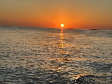 A stunning sunset over calm waters, creating a beautiful reflection — perfect for serene evening boat rides.