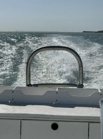 A view from the back of a boat as it speeds through shimmering waters, showcasing the vessel's wake and the surrounding scenery.