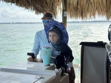 A child and an adult are seen at the helm of a boat, showcasing a cozy interior space perfect for navigating the waters.