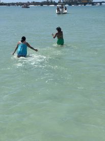 Two friends enjoy a fun day swimming in the clear waters, showcasing the perfect beach experience. Ideal for summer outings and water activities.