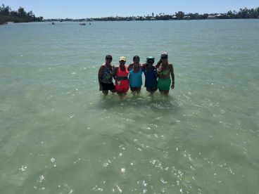 A group of friends enjoys a sunny day in shallow waters, celebrating and having fun at the beach — perfect for memorable summer outings.