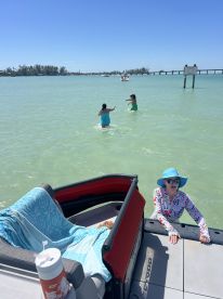 A fun day at the beach with two children playing in the water while an adult relaxes on the pontoon boat, showcasing the perfect family outing under the sun.