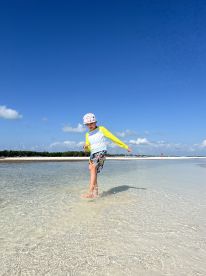 A child joyfully splashes in shallow waters at the beach, capturing the essence of fun and adventure in a tropical paradise.