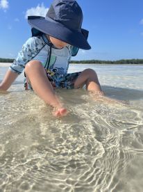 A child enjoys playing in the shallow waters at the beach, creating a joyful moment perfect for family outings and summer adventures.