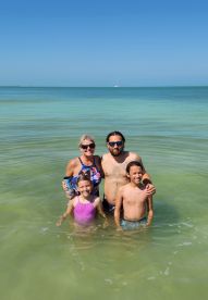 A joyful family enjoys a day at the beach, swimming in the clear waters — perfect for creating lasting memories together.