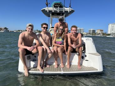 A cheerful group of young people enjoys a sunny day on a boat, capturing the essence of fun and adventure on the water.