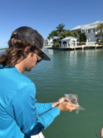 A fisherman holds a freshly caught fish while enjoying a sunny day on the water, showcasing the thrill of fishing adventures.