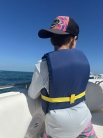 A young boy wearing a life jacket enjoys the view while boating, showcasing safety and fun on the water.