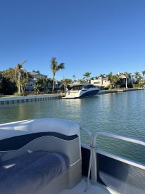 A serene view of a boat docked in a calm waterway, surrounded by palm trees and waterfront homes, perfect for a relaxing day on the water.