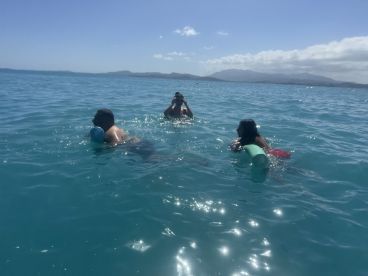 A group enjoys a refreshing swim in the stunning aquamarine waters, capturing the essence of fun and relaxation on a perfect day at sea.