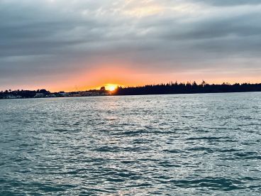 A serene sunset view over the water, showcasing the tranquil coastline — perfect for capturing the beauty of evening boat rides.