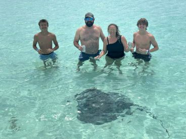 A family enjoys a memorable encounter with a stingray while wading in crystal-clear waters, creating unforgettable moments in nature.