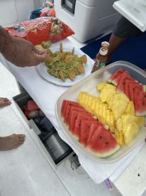 A delicious spread of guacamole, tortilla chips, watermelon, and pineapple on board, perfect for enjoying snacks while cruising on the water.
