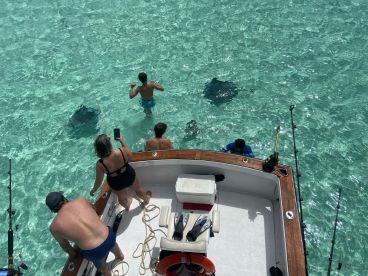 A group of people interacts with stingrays in crystal-clear waters, creating a memorable wildlife experience during their boating adventure.