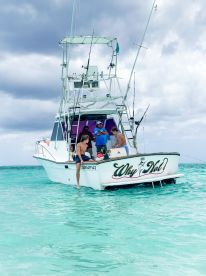 A group enjoys a fishing experience aboard the 'Why Not' boat in crystal-clear waters, showcasing the fun of a day on the water.