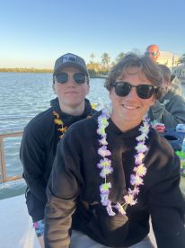 Two friends enjoy a fun moment on a boat, wearing leis and sunglasses, perfect for a day out on the water with friends.