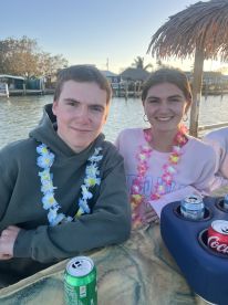 A cheerful couple enjoys drinks while wearing leis, capturing a festive moment on the water — perfect for celebrations and memorable outings.