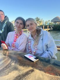 A cheerful group of friends enjoys their time on a boat, adorned with leis, perfect for a fun day out on the water.